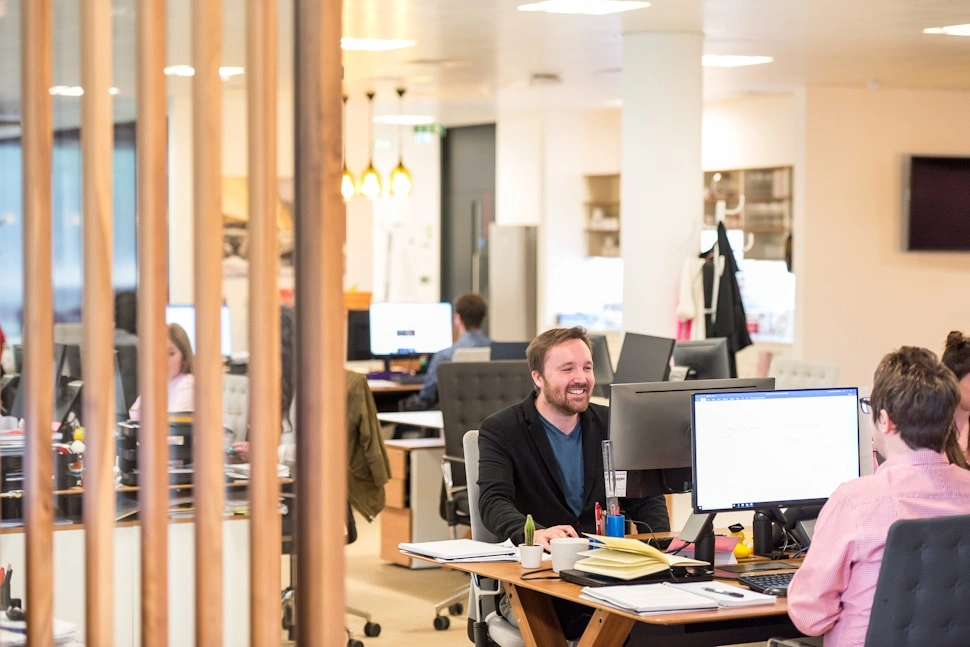A team member smiling at his monitor in a bright open office