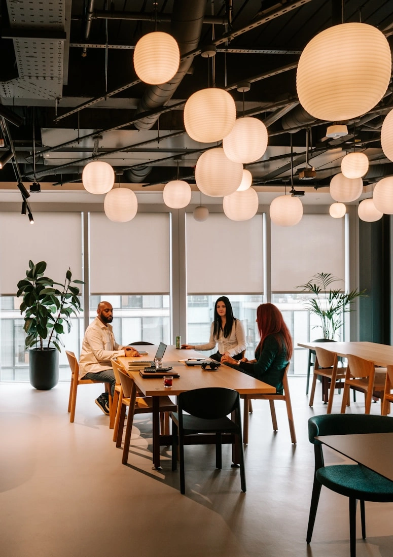 Colleagues in conversation at a long table under pendant lighting